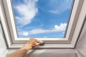 Man close new skylight (mansard window) in an attic room against blue sky Man close new skylight (mansard window) in an attic room against blue sky